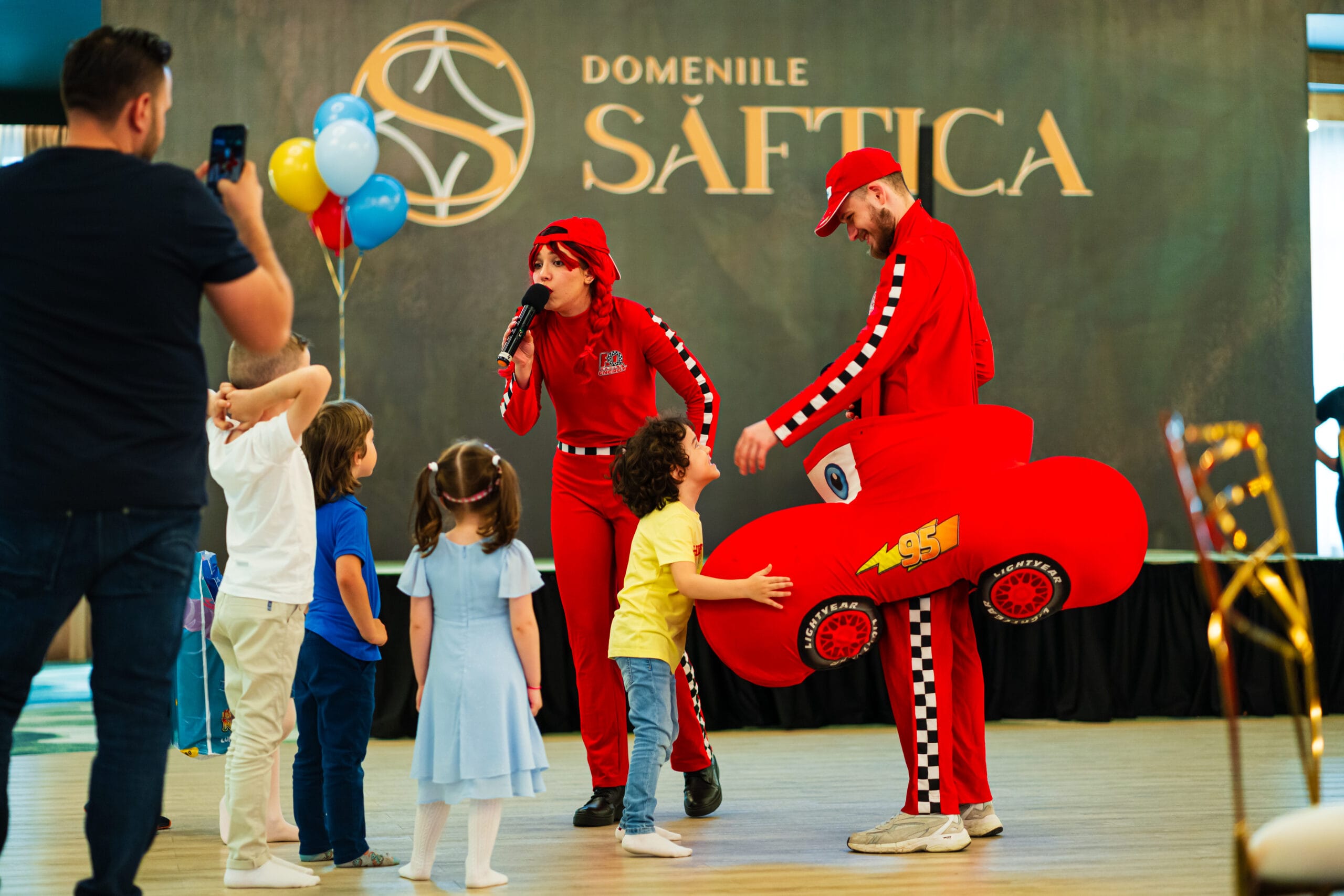 Eveniment la Domeniile Șăftica cu animatori costumați și copii. Un bărbat face poze.