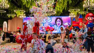 O petrecere cu confetti, animatori costumați, un castel gonflabil și un ecran mare cu textul "55".