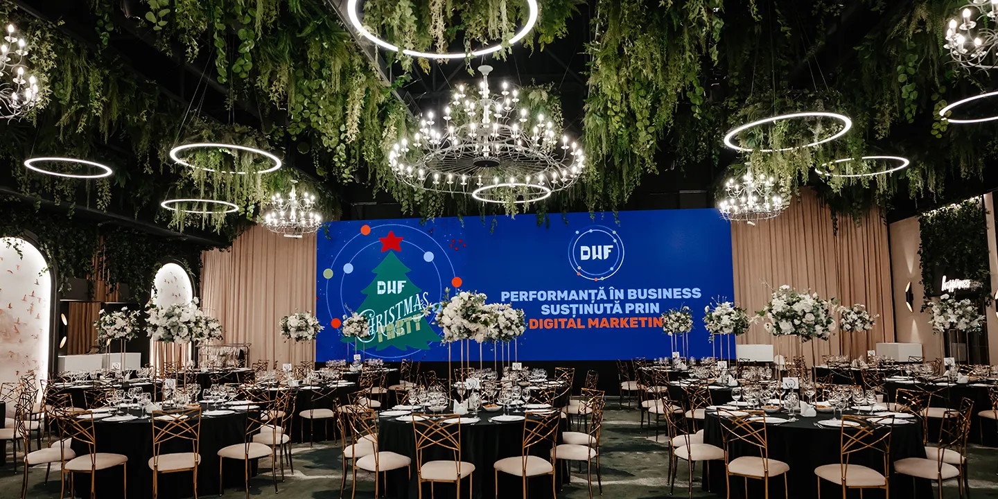Interior de eveniment: mese aranjate, ecrane cu "DHF Christmas Party" și "Performanță în Business susținută prin Digital Marketing".