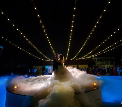 Un cuplu dansează pe un podium cu fum într-un spațiu de evenimente, cu lumini. Foto: FOTO.UMBRAVA.ro.