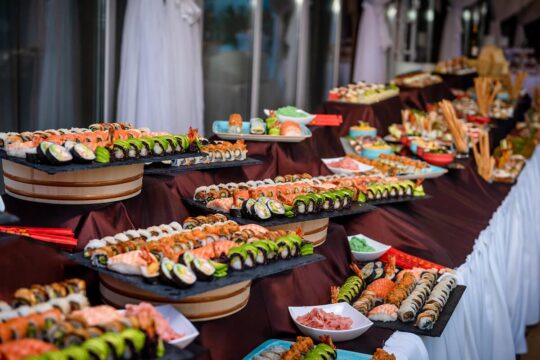 Bufet cu varietate de sushi, cu rulouri colorate și aranjamente atractive pe platouri, creând o masă îmbietoare.