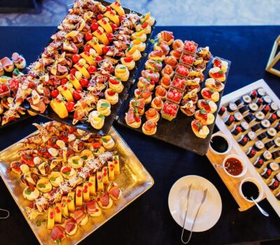 O imagine cu platouri cu aperitive și sushi aranjate pe o masă neagră.