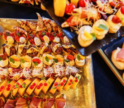 Două tăvi cu aperitive variate, inclusiv brânză, carne și bruschete.