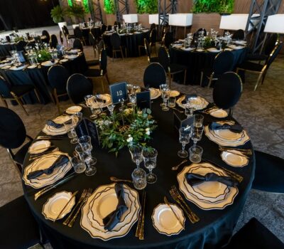 Scaune și mese rotunde negre decorate cu veselă elegantă pentru evenimente. Eticheta "12" a mesei este afișată.