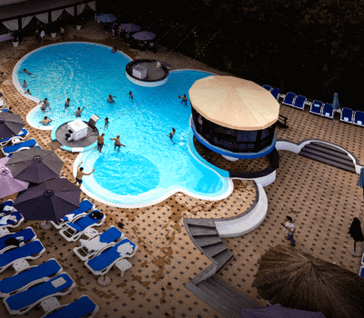 Vedere aeriană a unei piscine cu șezlonguri și umbrele de soare într-o stațiune.