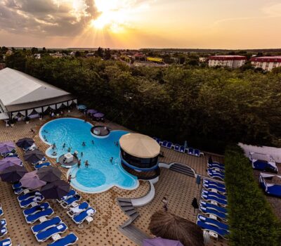 Vedere aeriană a unui complex turistic cu piscină și șezlonguri la apus.