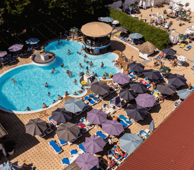O vedere aeriană a unei piscine aglomerate înconjurată de umbrele și șezlonguri.