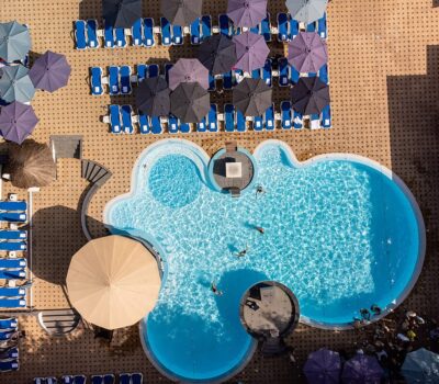 Vedere aeriană a unei piscine cu șezlonguri și umbrele de soare.