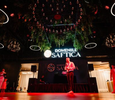 Interiorul Domeniilor Știrbei cu un orator, logo și iluminare festivă.