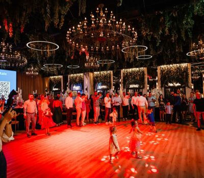 Eveniment interior cu oameni, lumini, candelabre și un ecran cu textul "Să construim Spitale cu Bani Privați!"