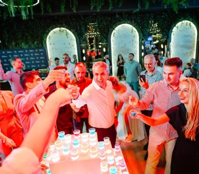 Un grup de oameni ciocnind pahare mici la o petrecere sau un eveniment.