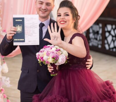Un cuplu căsătorit care deține un document românesc. Femeia are scris "I said yes!" pe mână.
