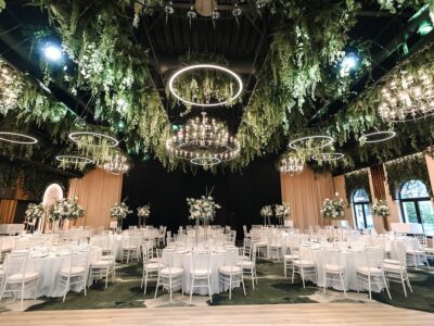 Interiorul elegant al sălii de bal are mese aranjate, aranjamente florale și candelabre decorative.