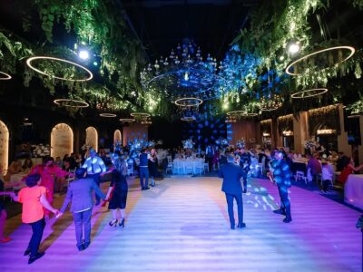 Oameni dansează pe o podea de dans la o nuntă, cu muzicieni cântând la instrumente.