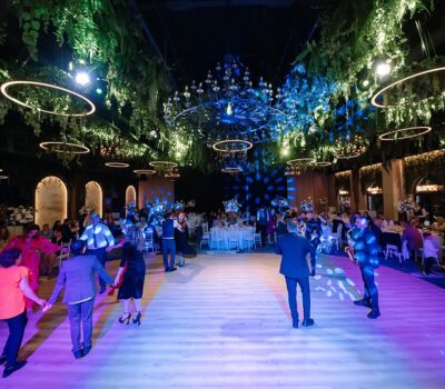 Oameni dansează pe o podea de dans la o nuntă, cu muzicieni cântând la instrumente.