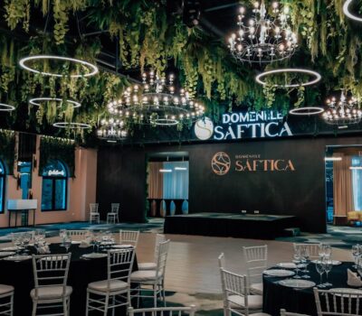 Interior Domeliile Saftica cu mese aranjate și vegetație suspendată. Scrie "DOMENIILE SAFTICA" pe perete.