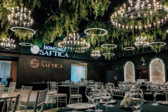 Interiorul Domnie Saftica cu candelabre, verdeață și mese aranjate.