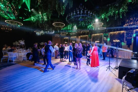 Oamenii se bucură și dansează pe ringul de dans într-o sală de bal decorată.