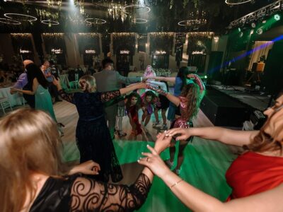 Un grup de oameni formează un cerc, cu mâinile împreunate, într-o cameră frumos decorată.