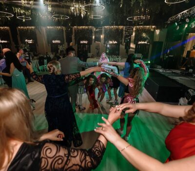 Un grup de oameni formează un cerc, cu mâinile împreunate, într-o cameră frumos decorată.