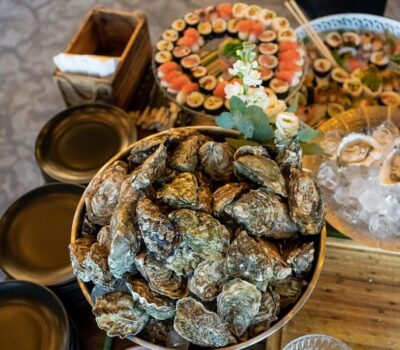 O masă cu stridii crude, sushi și farfurii goale, într-o prezentare de restaurant sau bufet.