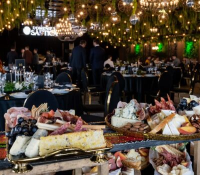 Sală de evenimente decorată cu platouri cu brânzeturi, carne, fructe. Logo-ul "Domeniul Saftica" este vizibil.