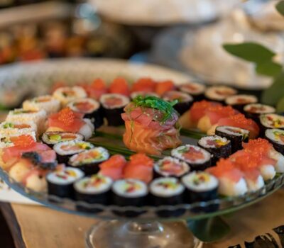 Un plat transparent cu sushi variat, inclusiv rulouri și nigiri.