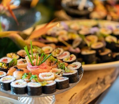 Diverse selecție de sushi pe platouri, cu flori și ghimbir.