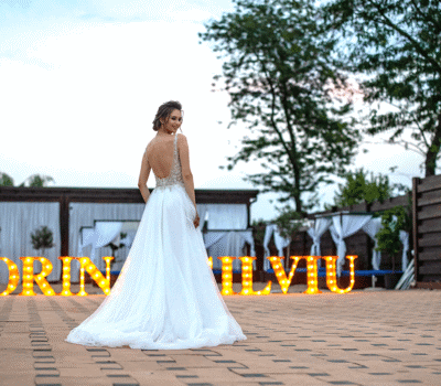 O mireasă se uită peste umăr lângă lumini cu mesajul "SORIN SILVIU".