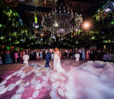 Dansând la o nuntă, mirele sărutând mâna miresei, luminile disco strălucesc, plafon verde.