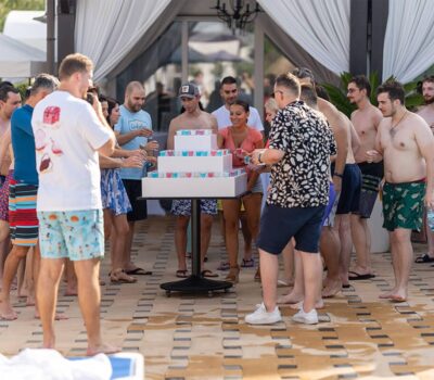 Un grup de oameni se adună în jurul unei piramide din pahare de shoturi.