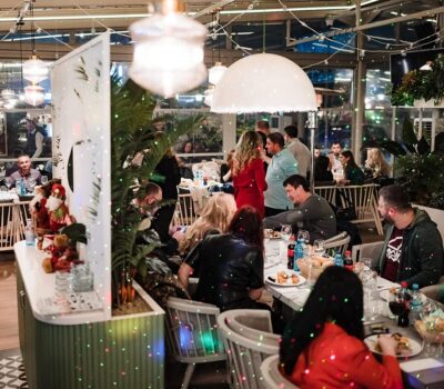 Oameni stând la mese într-un restaurant cu iluminare decorativă.