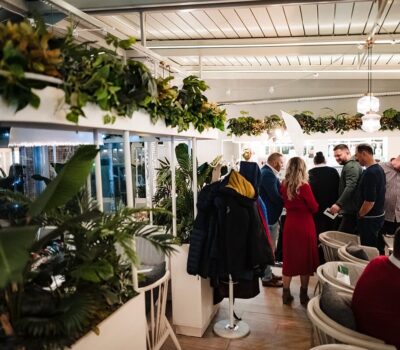 Un grup de oameni stând într-un restaurant cu plante și haine.