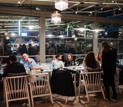 Un grup de oameni stau în jurul unei mese într-un restaurant cu lumini deasupra.