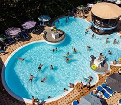 Vedere aeriană a unei piscine cu oameni, umbrele și șezlonguri.