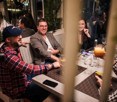 Grup de oameni se bucură de băuturi și conversații la o masă într-un restaurant.