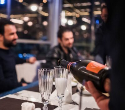 Servire șampanie la o întâlnire. Bărbați în fundal.