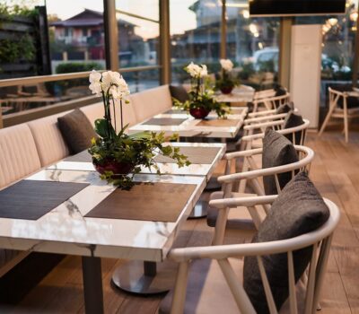 Interiorul elegant al restaurantului cu scaune și mese albe, cu decorațiuni florale.