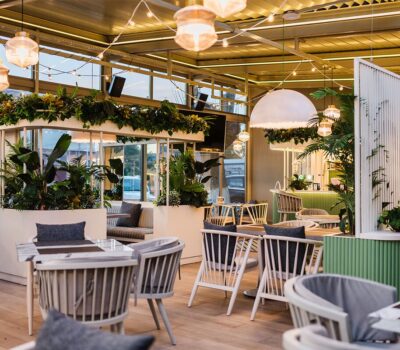 Interior luminos și elegant al unui restaurant cu plante și scaune moderne.