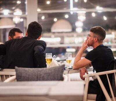 Într-un restaurant, bărbați beau bere, unul fumează.