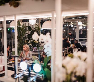 Oameni care iau masa într-un restaurant cu decorațiuni verzi și iluminat moale.