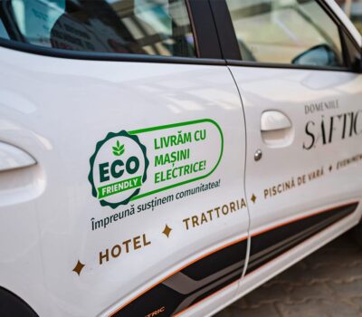 Mașină electrică albă Domeniile Șăftica, „Eco Friendly Livrăm cu mașini electrice!” Hotel, Trattoria, Piscină.