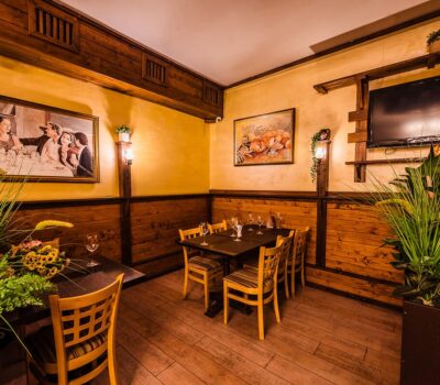 Interiorul unui restaurant cu pereți din lemn, opere de artă, o masă și plante.