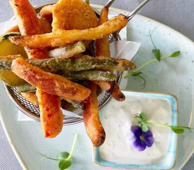 Friteze de legume cu sos de iaurt pe farfurie albastră.