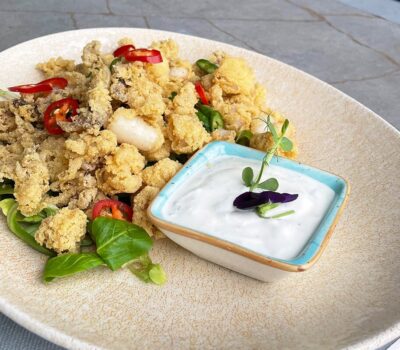 Farfurie cu calamari prăjiți, ardei roșii și un sos alb într-un castron.