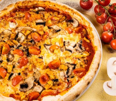 O pizza delicioasă cu ciuperci, roșii și brânză apetisantă, gata de savurat.