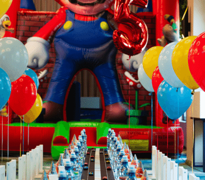 O petrecere aniversară cu gonflabile Mario, baloane și masă cu tematică "Cars" și numărul 5.