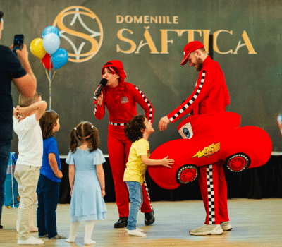 Eveniment la Domeniile Șăftica. Copii se uită la animatori îmbrăcați în roșu cu fulger McQueen.
