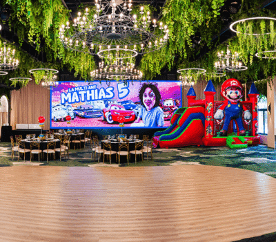 Interiorul spațios al sălii de petrecere pentru a 5-a aniversare a lui Mathias. Balon gonflabil Mario, decor mașini, mese.