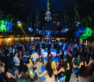 Oameni care dansează într-un spațiu de evenimente decorat cu plante și lumini ambientale.